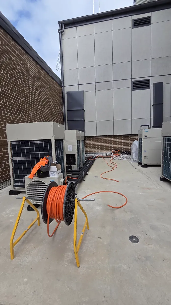Commercial HVAC condenser units with orange cable on a reel during installation