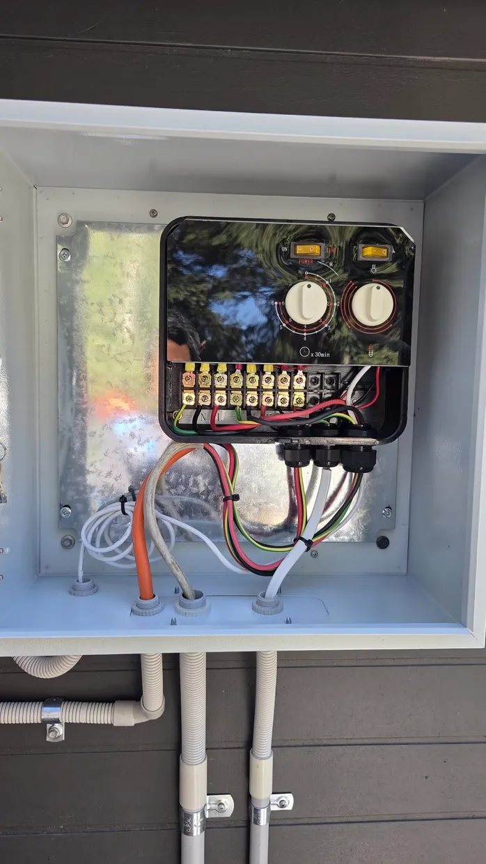 Outdoor control box with timer dial and power switches, wiring through cable glands into conduit