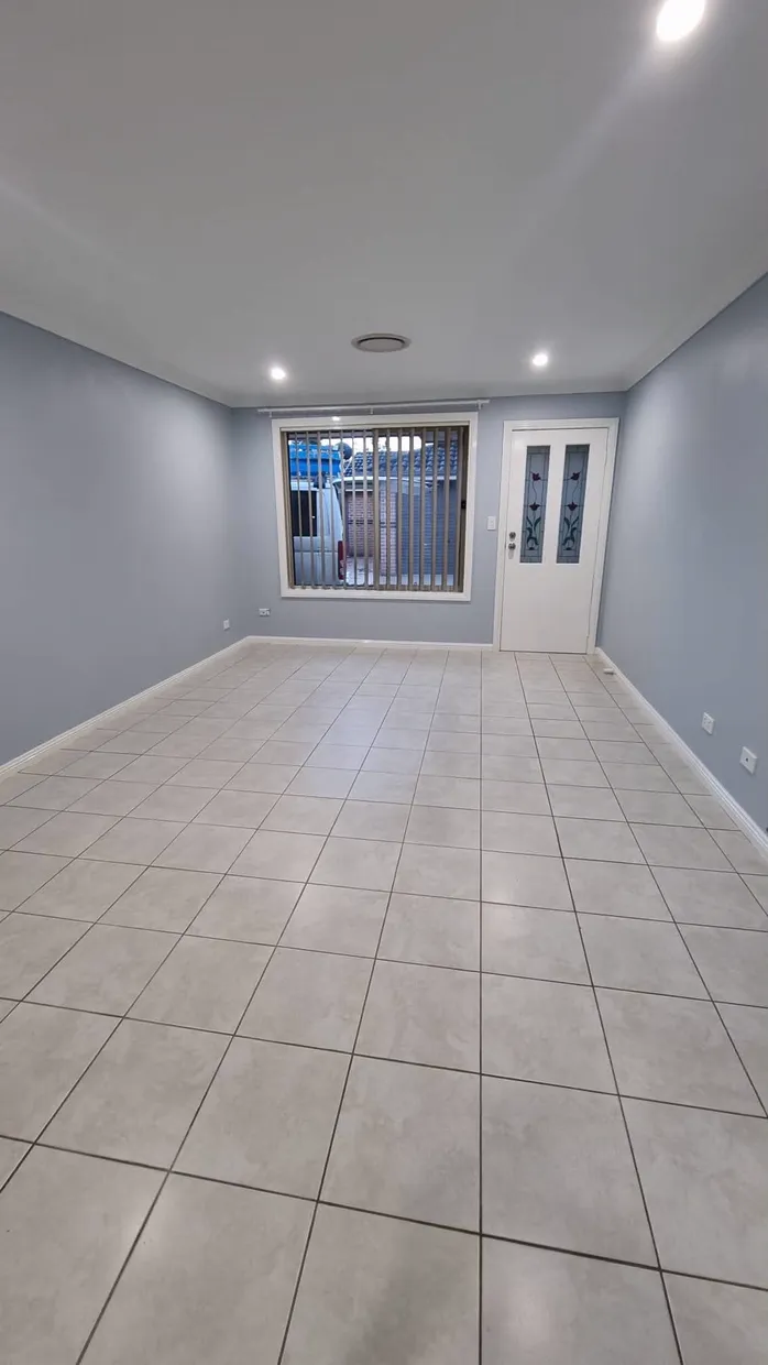 Tiled hallway lit by evenly spaced ceiling downlights running to the front door