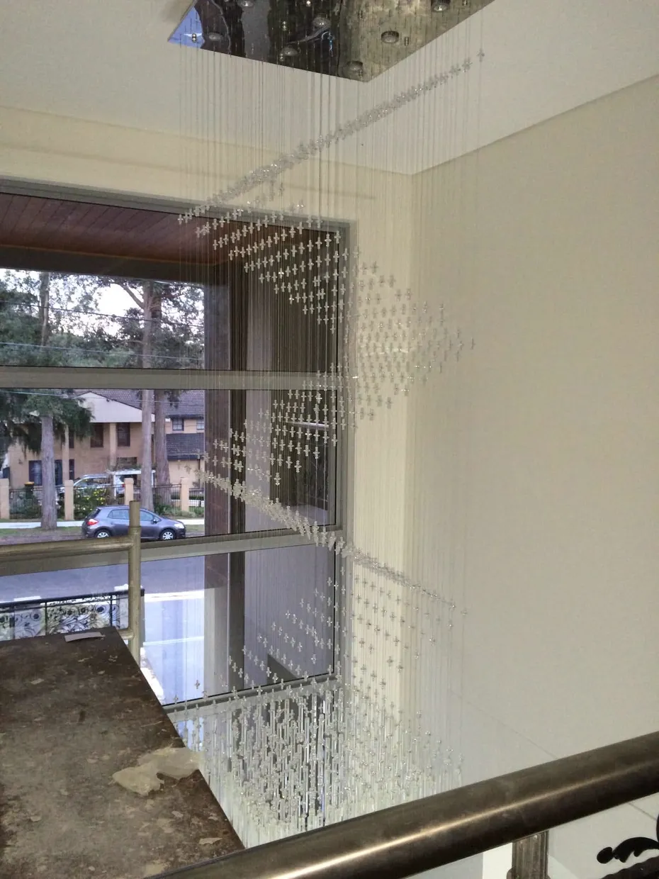 Long cascading crystal pendant light hanging through a stairwell void