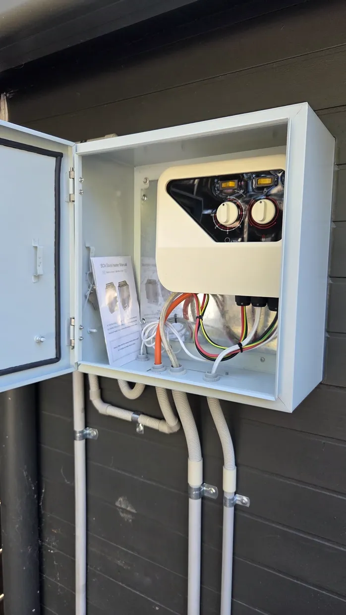 Sauna heater control unit in an exterior enclosure with conduit runs down a wall