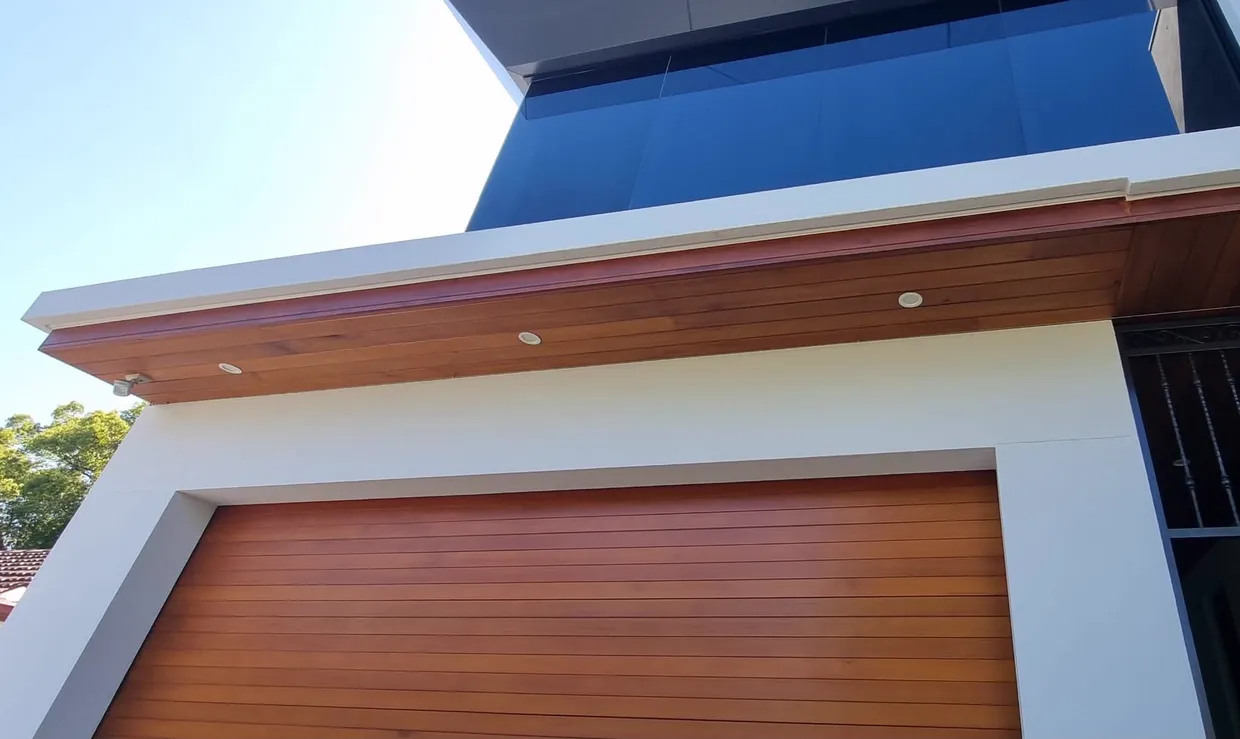 Recessed downlights set into a timber soffit above a timber garage door