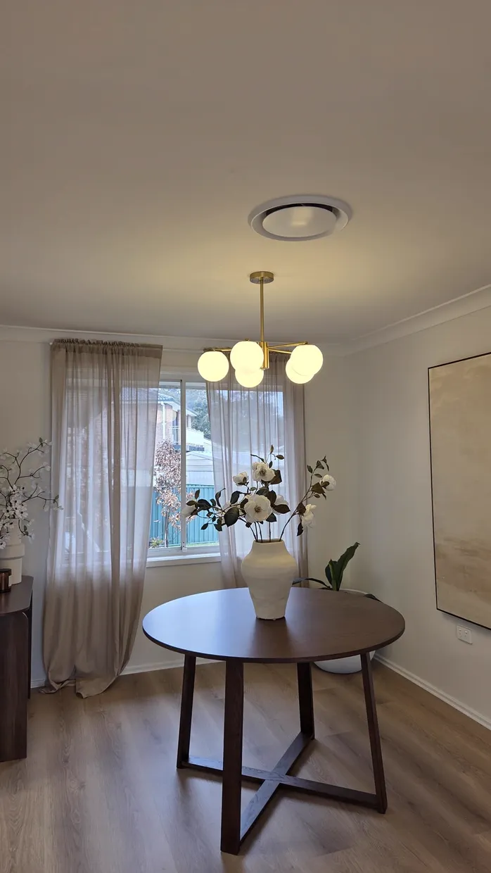 Brass multi-arm sputnik chandelier with frosted glass globes installed above a dining table with a vase of flowers